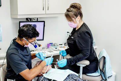 Dr. Gomes and his assistant providing emergency dentistry services for a patient