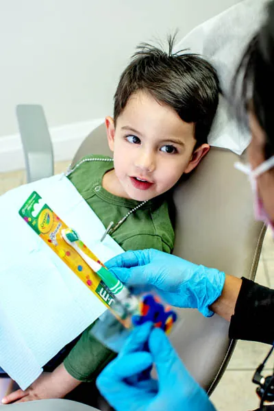 Dentistry by the Bay hygienist giving a young patient a toothbrush after his appointment